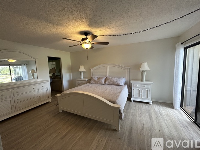 A bedroom with a large bed, a dresser, and a ceiling fan.