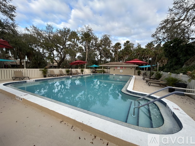 A large outdoor swimming pool surrounded by trees and a fence.
