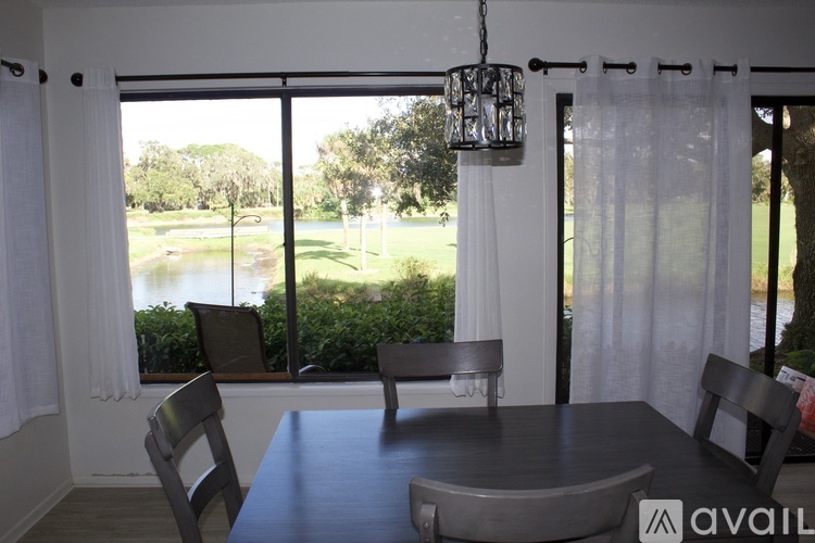 A dining room with a table and chairs and a view of a pond outside.
