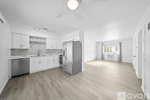 A spacious kitchen with white cabinets and a wooden floor.