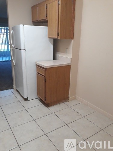 A kitchen with a white fridge and wooden cabinets.