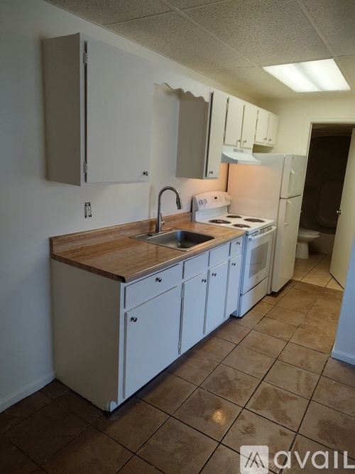 A kitchen with white cabinets and a wooden counter top.