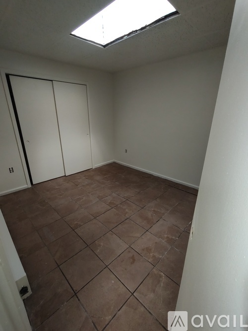 A room with brown tiled flooring and white walls.
