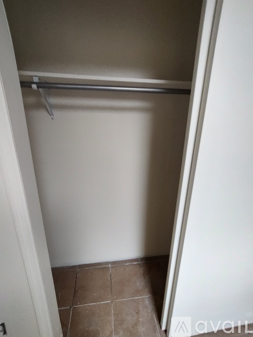 A white closet with a shelf and a white door.