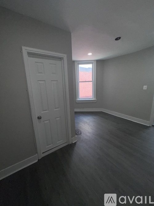 A room with a white door and a window with red curtains.