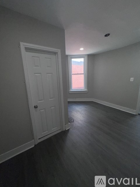 A room with a white door and a window with red curtains.