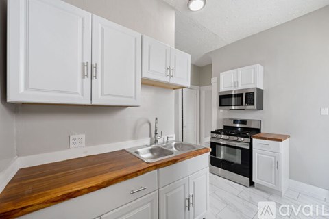A kitchen with white cabinets and a wooden countertop.