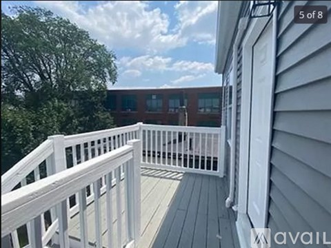 A white deck with a railing and a building in the background.