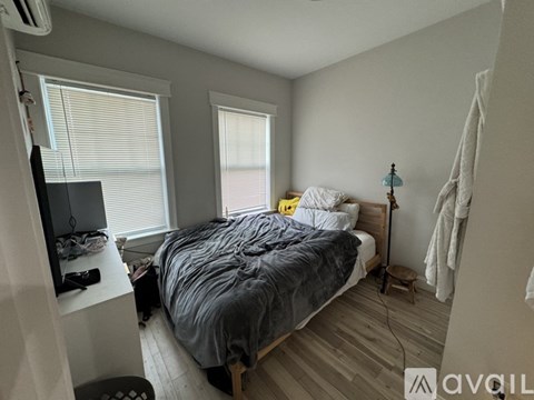 A bedroom with a bed, a television, and a window with blinds.