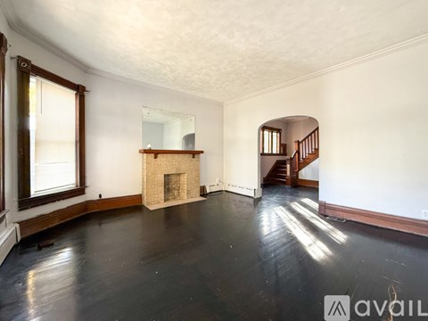A spacious room with a fireplace and a staircase.