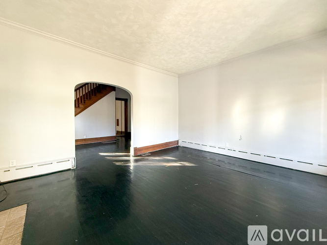 A spacious room with a wooden floor and a white wall.