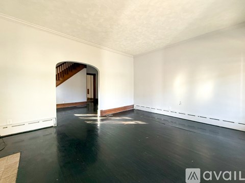A spacious room with a wooden floor and a white wall.