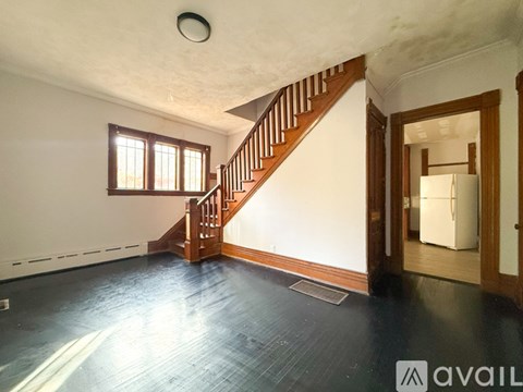 A spacious room with a wooden staircase and a window.