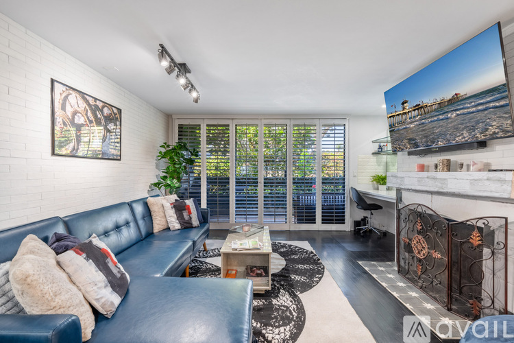 A living room with a blue couch and a television on the wall.