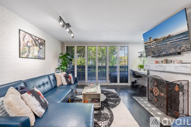 A living room with a blue couch and a television on the wall.