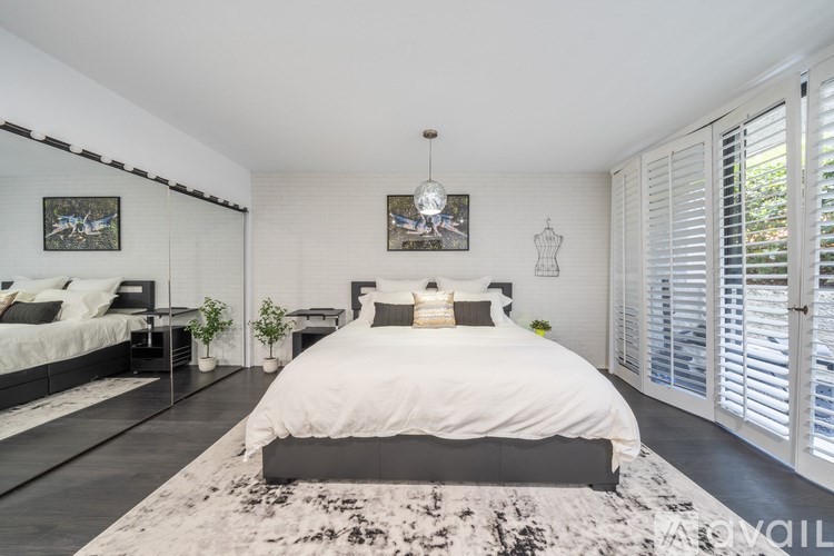 A bedroom with a large bed and a rug in the center.