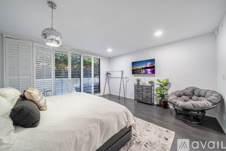 A modern bedroom with a large bed and a grey chair.