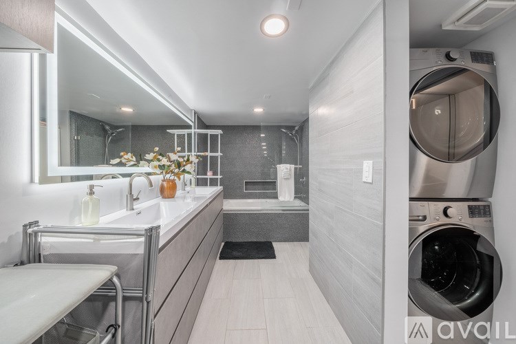 A modern bathroom with a washer and dryer built into the wall.
