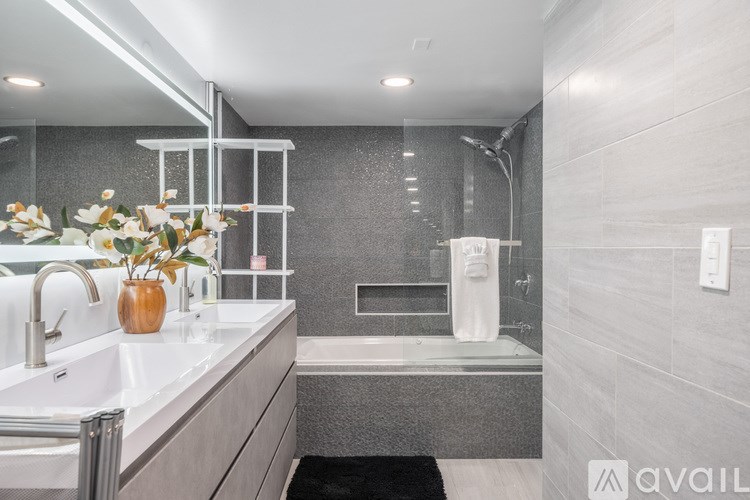 A modern bathroom with a sink, mirror, and shower area.