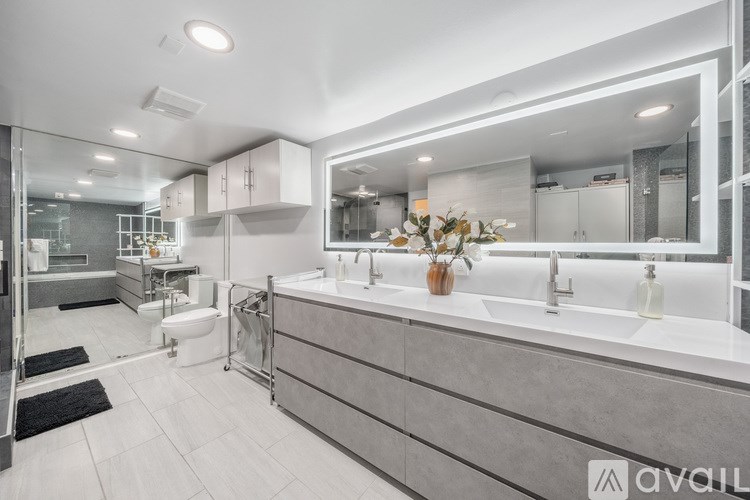 A modern bathroom with a large mirror and a sink vanity.