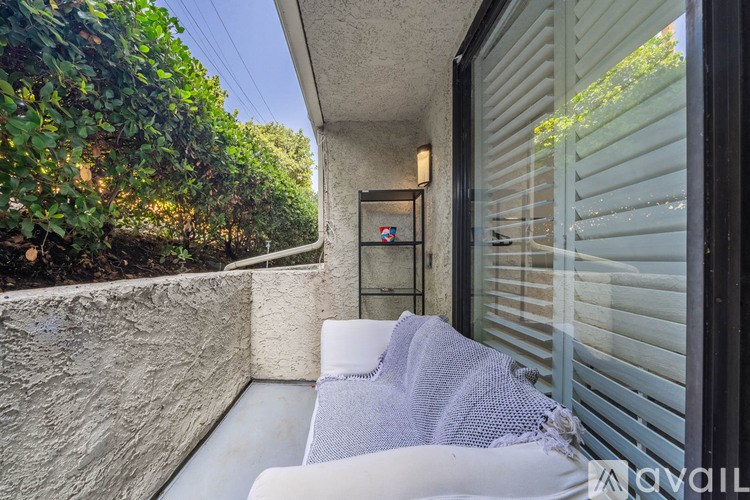 A white couch is on a patio with a grey blanket on it.