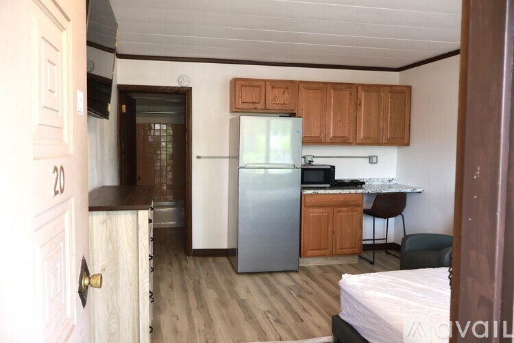 A small room with a bed, desk, and refrigerator.