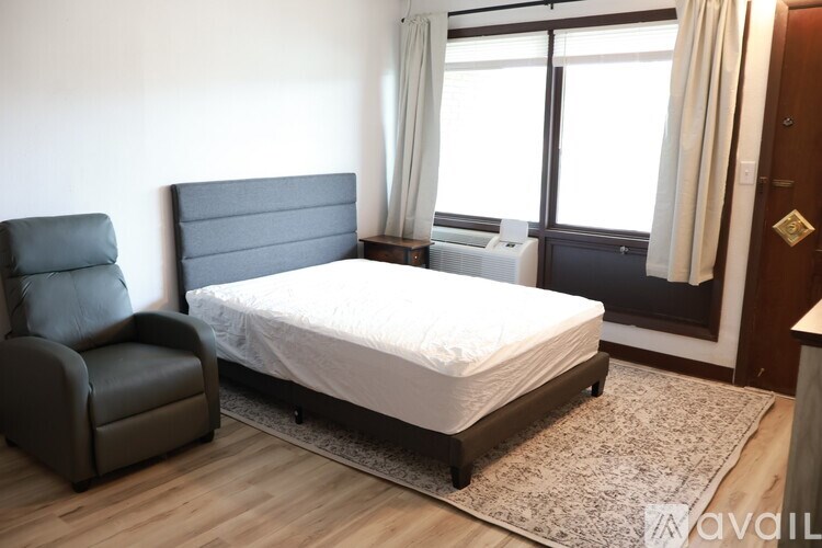 A bedroom with a large bed, a chair, and a window.