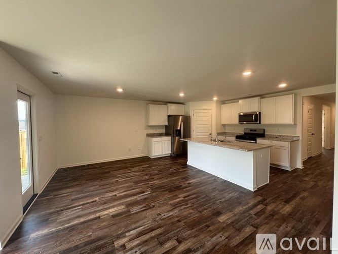 A spacious kitchen with white cabinets and a wooden floor.