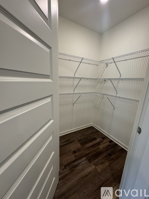 A walk-in closet with white shelving and wooden floors.