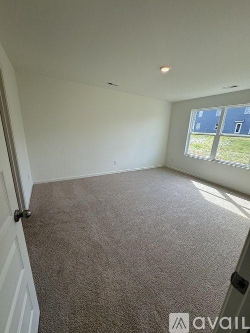 A room with carpeted floor and a window letting in natural light.