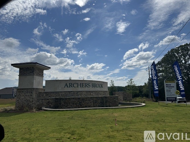 The image shows a sign that reads "ARCHERS BROOK" in front of a grassy area with a clear blue sky.