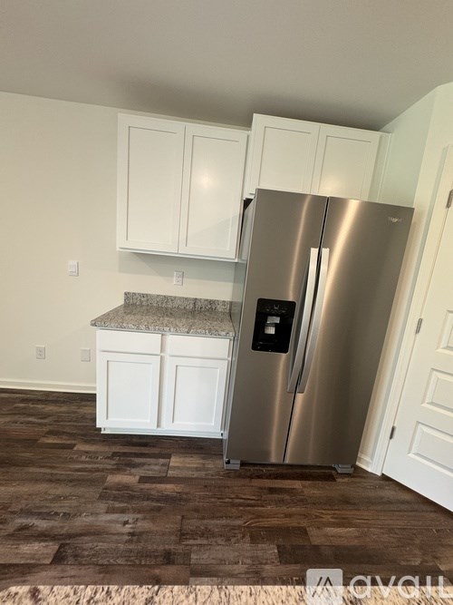 A kitchen with a stainless steel refrigerator and white cabinets.