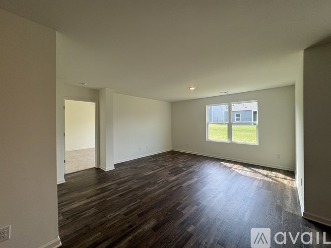 A spacious room with wooden floors and a large window.