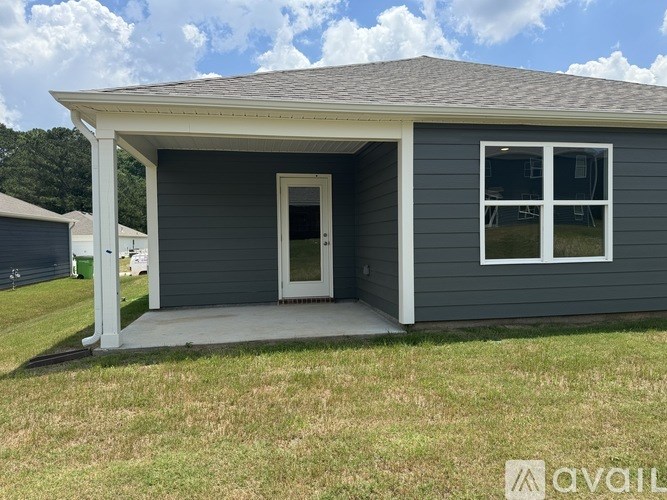 A small house with a grey exterior and a white door and window.