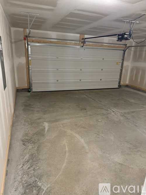 A garage with a white door and a concrete floor.