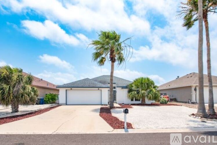 A house with a driveway and palm trees in front.