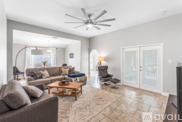 A living room with a grey couch, a brown coffee table, and a ceiling fan.