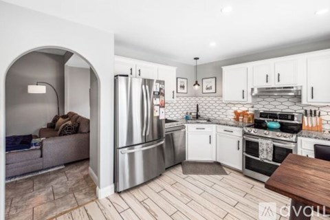 A kitchen with white cabinets and a wooden table.