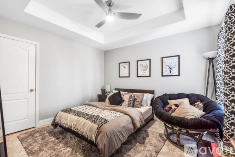 A bedroom with a bed, a chair, and pictures on the wall.