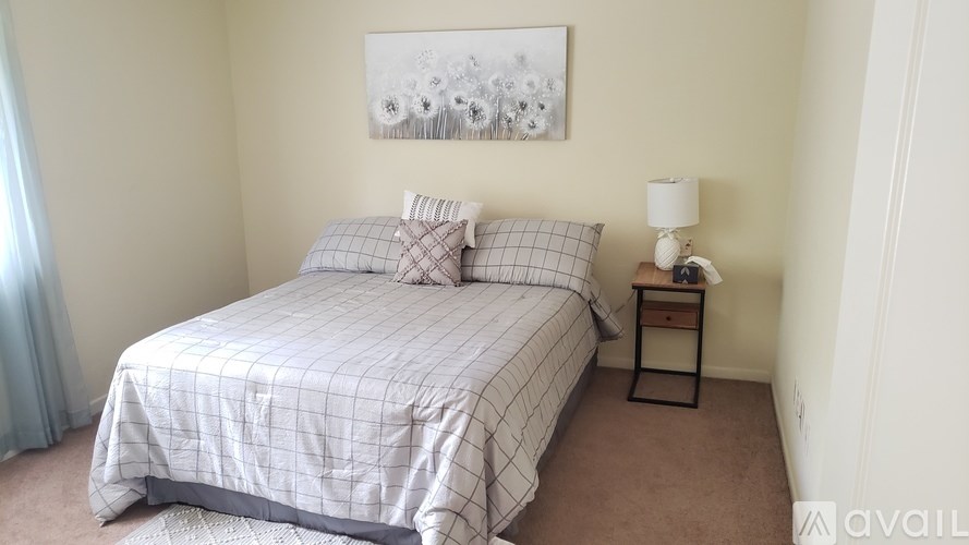 A bedroom with a bed, nightstand, and a painting on the wall.