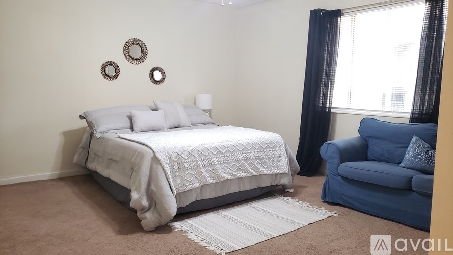 A bedroom with a large bed and a blue chair.