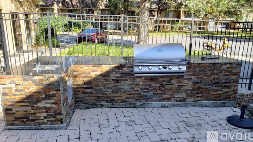 A stone wall with a grill on top and a black chair in front.
