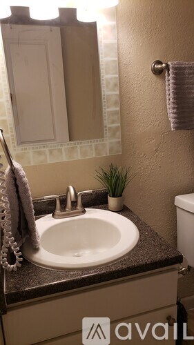 A bathroom with a sink, mirror, and towel.