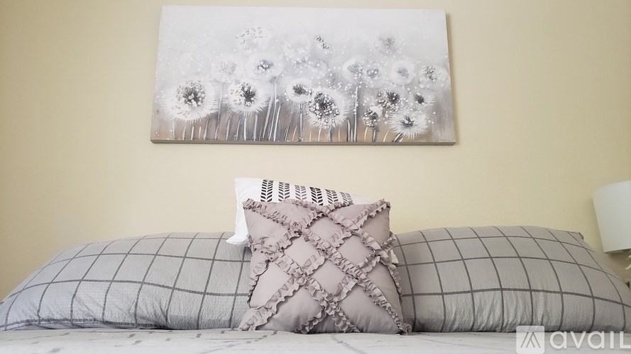 A bed with a grey pillow and a painting of flowers on the wall.