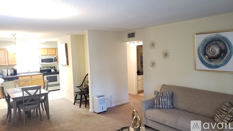 A living room with a grey couch and a painting on the wall.