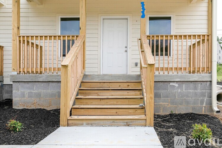 A wooden staircase leads to a white door on a house.
