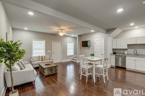 A well-lit, spacious kitchen and living room with white furniture and wooden floors.
