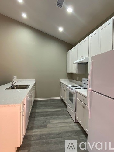 A kitchen with white cabinets and a pink refrigerator.