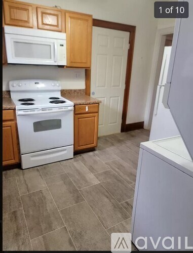 A kitchen with a white oven and microwave, wooden cabinets, and a white refrigerator.