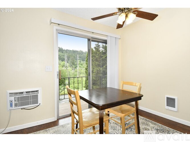A dining room with a table and chairs and a sliding glass door.